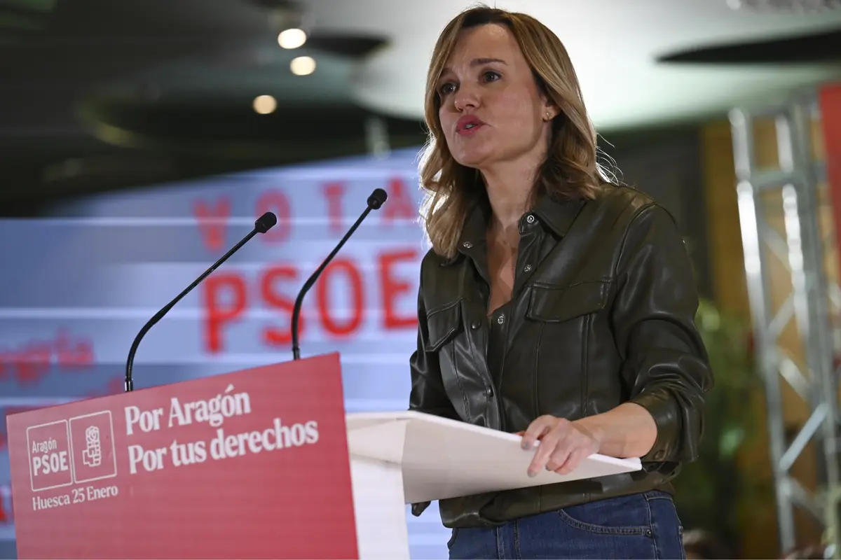 Mujer hablando en un mitin del PSOE en Aragón detrás de un atril rojo con el lema Por Aragón Por tus derechos