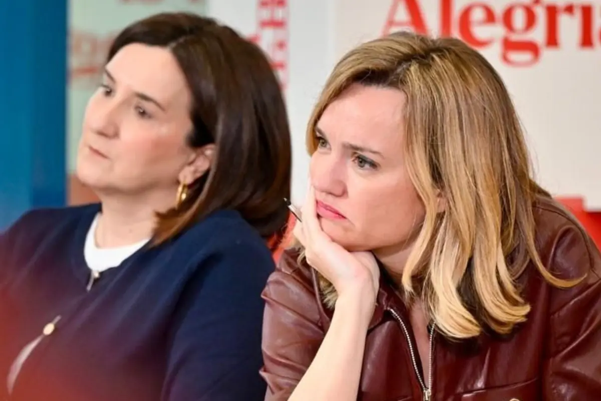 Dos mujeres sentadas en un acto público escuchan con gesto serio y pensativo, una con chaqueta oscura y la otra con chaqueta de cuero marrón apoyando la cara en la mano Dos mujeres sentadas en un acto público escuchan con gesto serio y pensativo, una con chaqueta oscura y la otra con chaqueta de cuero marrón apoyando la cara en la mano