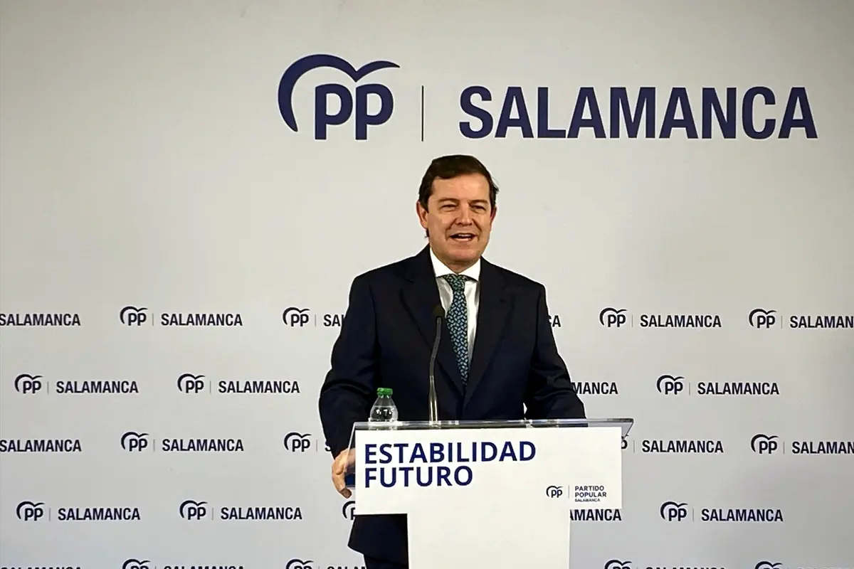 Hombre con traje hablando en un atril del Partido Popular en Salamanca con el lema Estabilidad Futuro impreso en el frontal