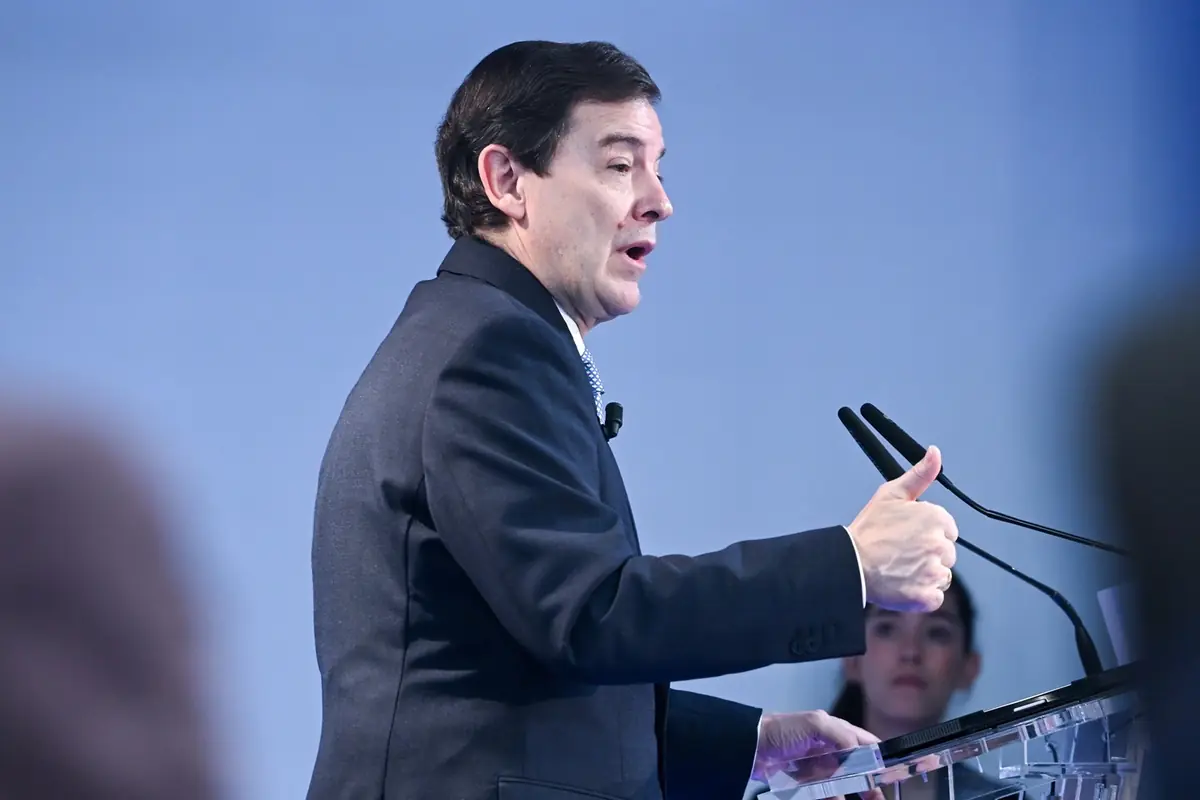 Hombre con traje oscuro hablando en un atril y levantando el pulgar durante una conferencia Hombre con traje oscuro hablando en un atril y levantando el pulgar durante una conferencia