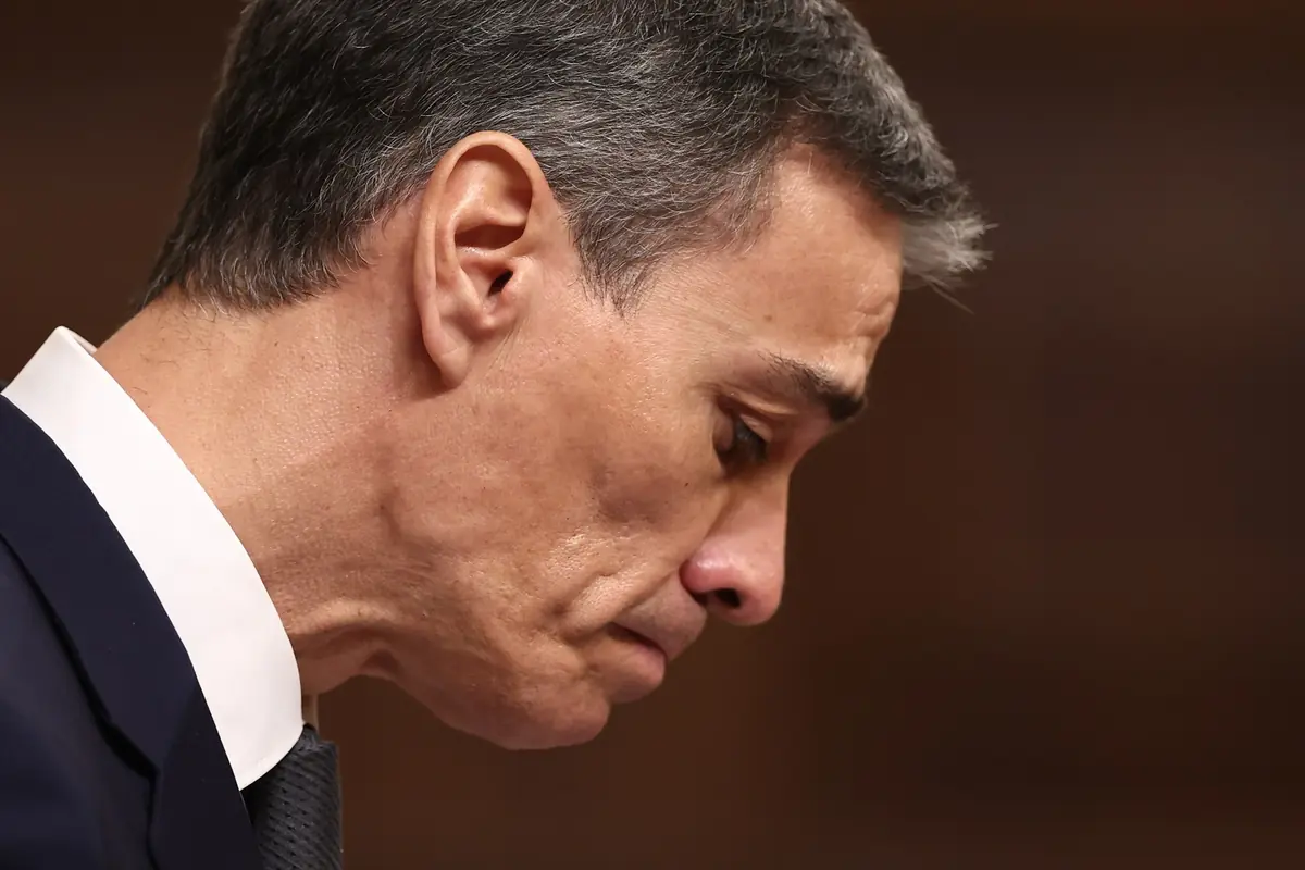 Primer plano de un hombre de mediana edad con traje oscuro y gesto serio mirando hacia abajo