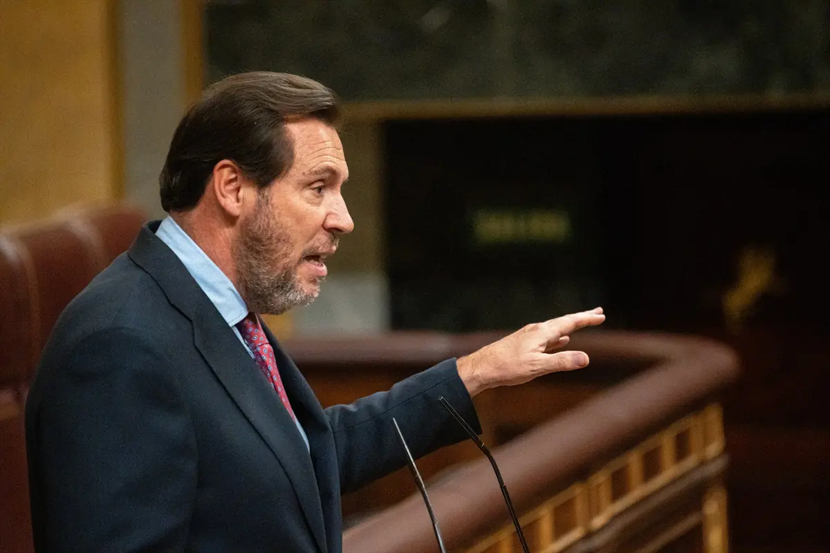 Hombre de mediana edad con barba y traje oscuro hablando y gesticulando en un parlamento o hemiciclo