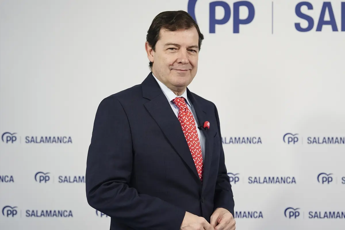 Hombre con traje oscuro y corbata roja posando frente a un fondo con el logotipo del PP y la palabra Salamanca