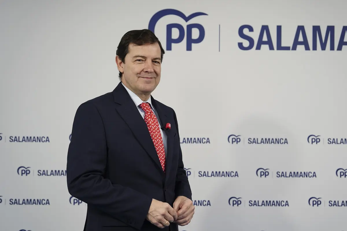 Hombre con traje oscuro y corbata roja posando frente a un fondo con el logotipo del PP y la palabra Salamanca