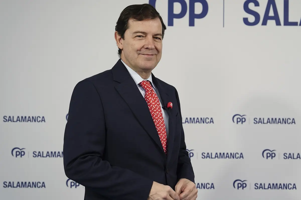 Hombre con traje oscuro y corbata roja posando ante un fondo con el logotipo del PP y la palabra Salamanca