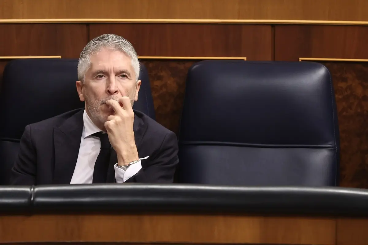 Hombre de cabello canoso con traje oscuro sentado pensativo en un escaño de un parlamento