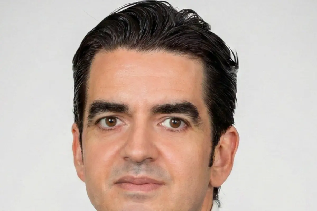 Retrato de un hombre de mediana edad con cabello oscuro peinado hacia atrás y expresión seria sobre fondo claro