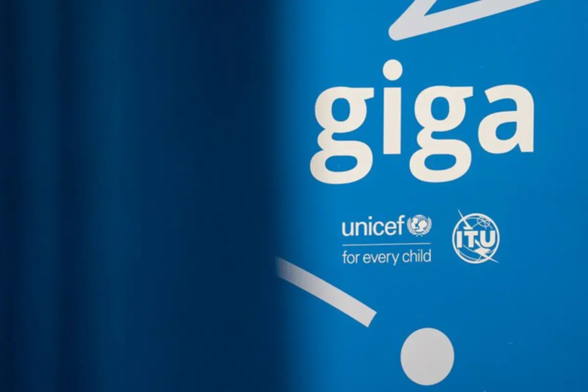 Cartel azul del proyecto Giga con los logotipos de UNICEF y la UIT y el lema for every child parcialmente cubierto por una cortina azul