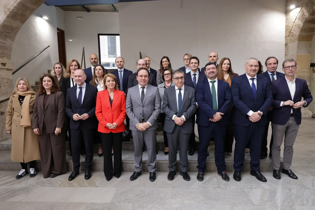 Grupo de hombres y mujeres con ropa formal posando para una foto oficial en el interior de un edificio institucional