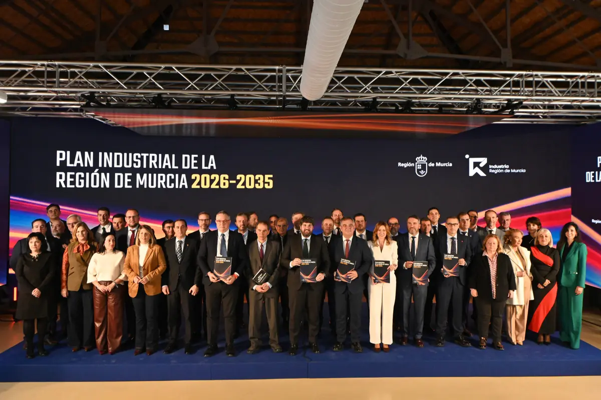 Grupo de autoridades y representantes posando en un escenario durante la presentación del Plan Industrial de la Región de Murcia 2026-2035 con un gran panel informativo de fondo