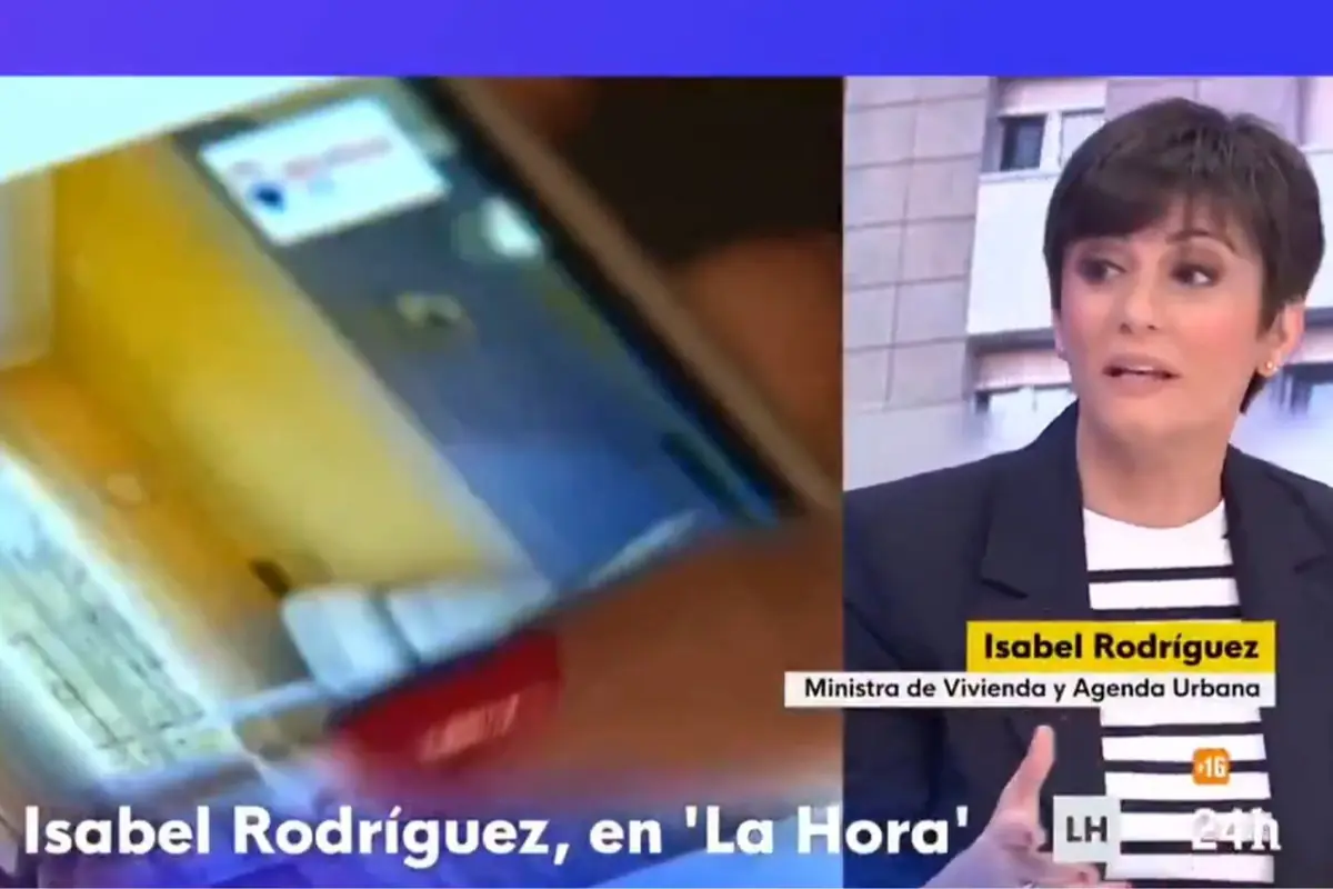 Captura de un programa de televisión donde una presentadora entrevista a Isabel Rodríguez, identificada en un rótulo como ministra de Vivienda y Agenda Urbana, con un móvil desenfocado mostrado a la izquierda de la pantalla