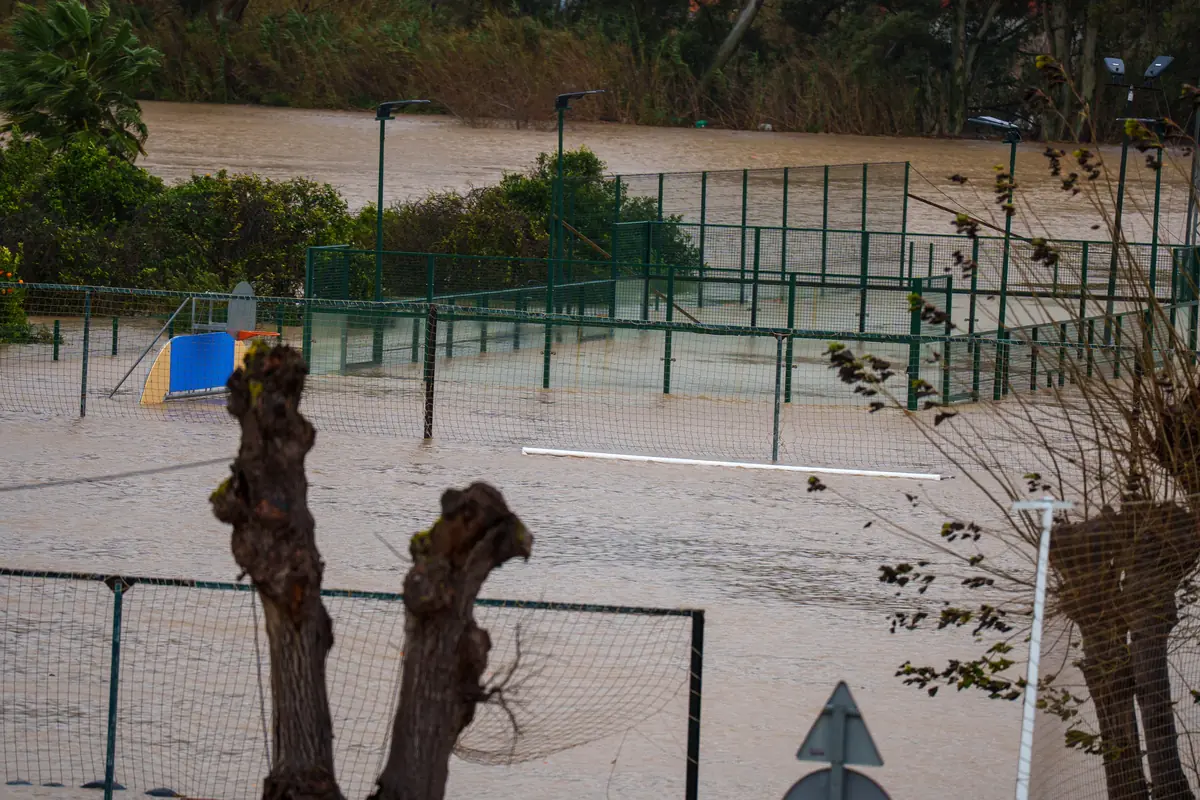Cancha deportiva al aire libre completamente inundada por una crecida de agua que cubre el suelo y las vallas de metal