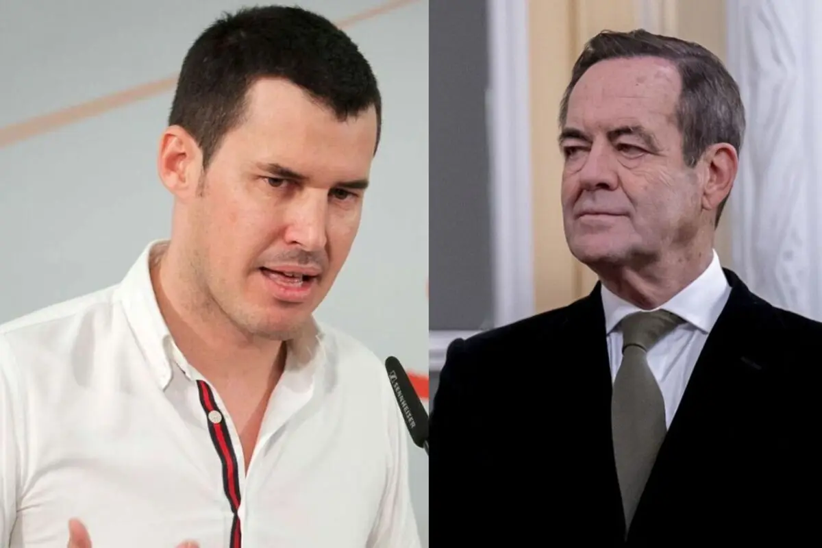 Dos hombres en plano medio uno joven con camisa blanca hablando ante un micrófono y otro mayor con traje oscuro y corbata clara mirando hacia la izquierda