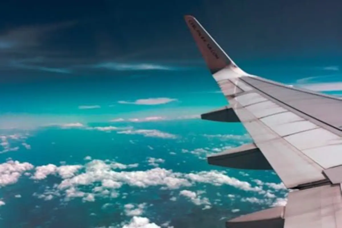 Vista del ala de un avión sobrevolando un cielo azul con nubes blancas