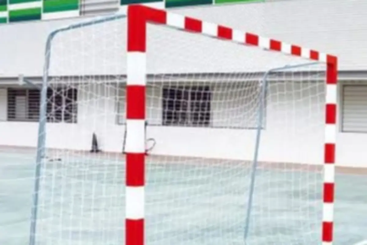 Portería con postes rojos y blancos y red blanca en una pista deportiva exterior