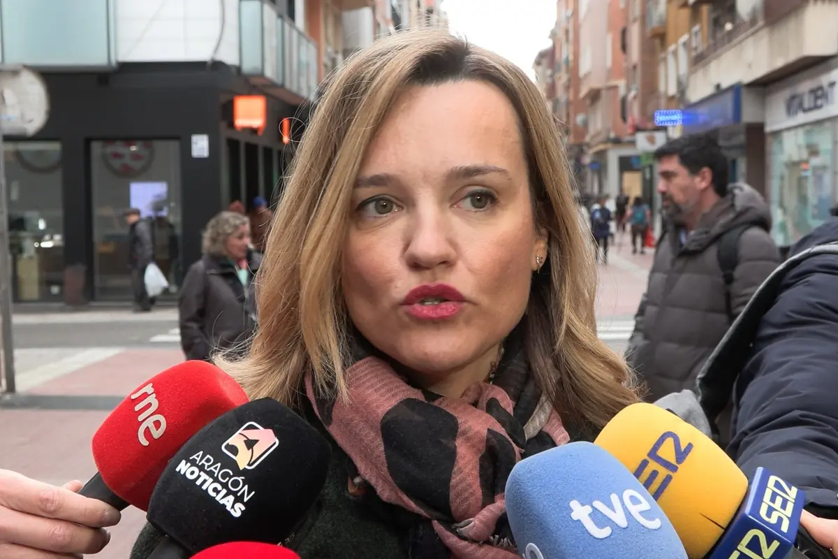 Mujer hablando en la calle rodeada de micrófonos de varios medios de comunicación españoles