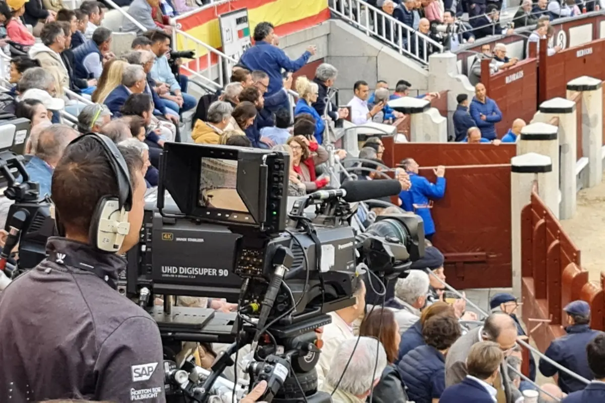 Cámara de televisión profesional grabando un evento taurino en una plaza llena de público en las gradas