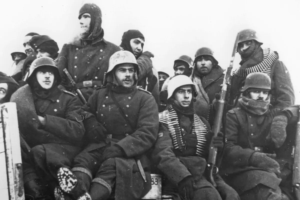 Grupo de soldados con abrigos de invierno y cascos sentados juntos en un vehículo durante una escena de guerra en clima frío