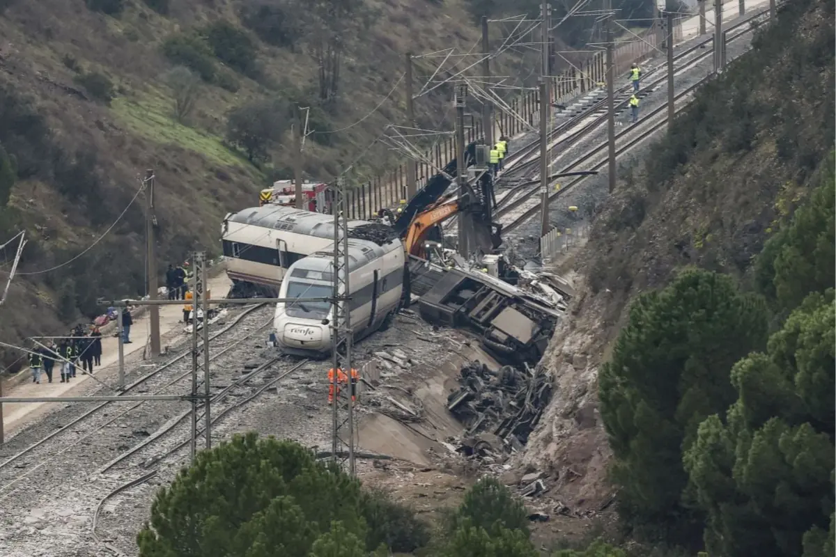 Accidente ferroviario con un tren descarrilado junto a restos de un camión volcado y equipos de emergencia trabajando en la vía en una zona montañosa Accidente ferroviario con un tren descarrilado junto a restos de un camión volcado y equipos de emergencia trabajando en la vía en una zona montañosa