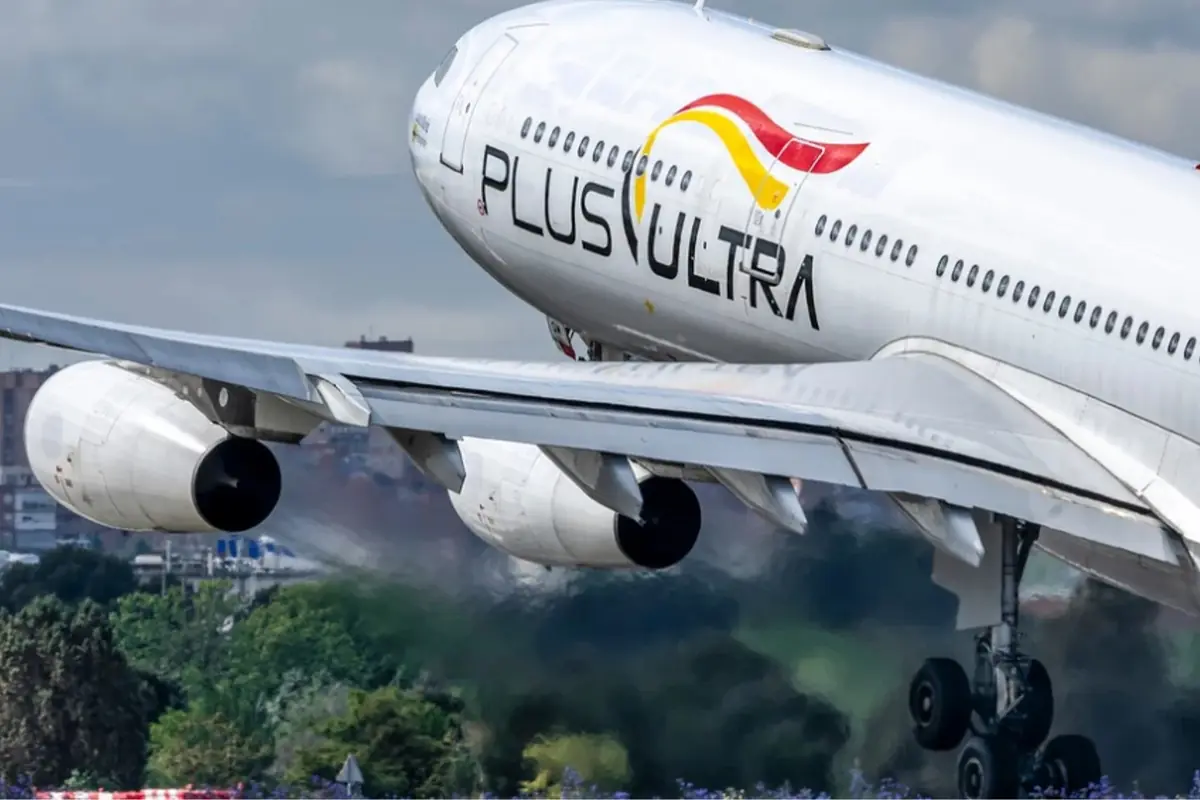 Avión comercial de la aerolínea Plus Ultra despegando con el tren de aterrizaje aún extendido sobre una zona verde