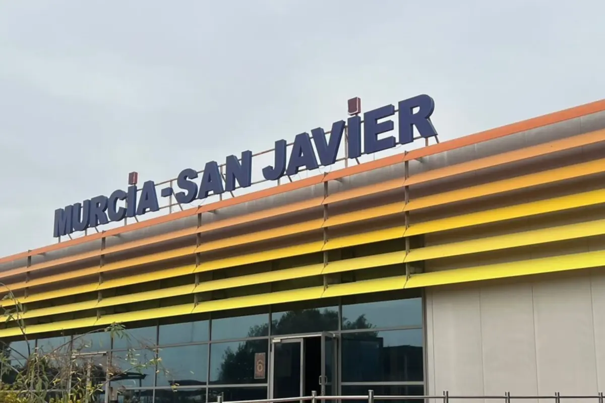 Fachada del edificio del aeropuerto Murcia San Javier con letrero azul sobre estructura de lamas horizontales amarillas y naranjas Fachada del edificio del aeropuerto Murcia San Javier con letrero azul sobre estructura de lamas horizontales amarillas y naranjas