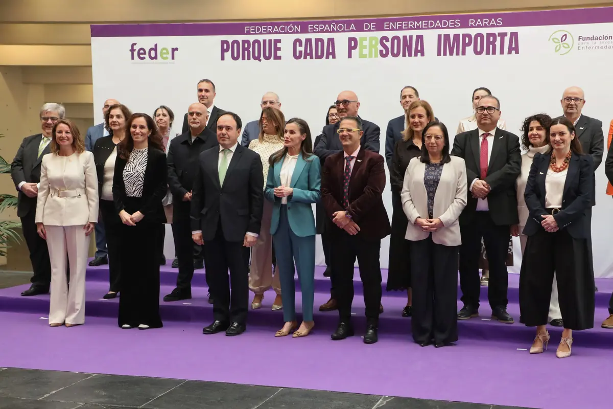 Grupo de personas posando en un escenario con alfombra morada frente a un cartel de la Federación Española de Enfermedades Raras con el lema Porque cada persona importa Grupo de personas posando en un escenario con alfombra morada frente a un cartel de la Federación Española de Enfermedades Raras con el lema Porque cada persona importa