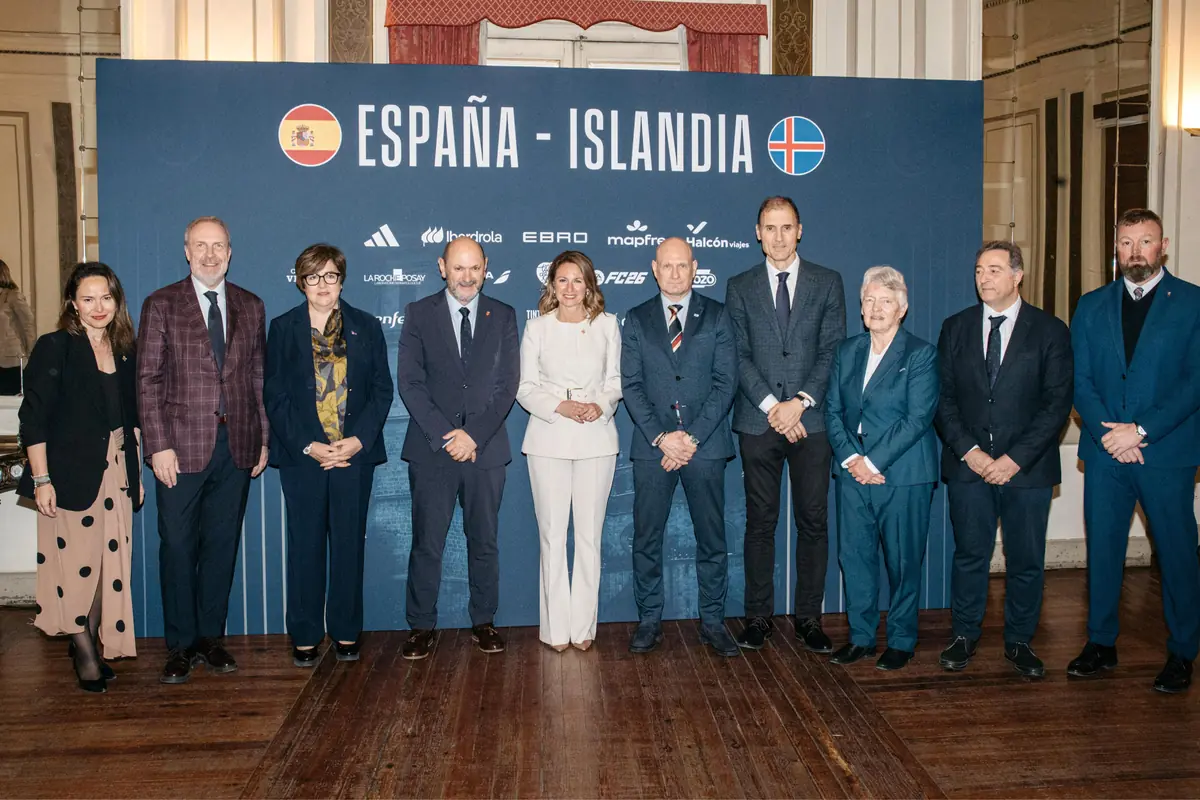 Grupo de representantes de España e Islandia posando de pie frente a un panel azul con los nombres de ambos países y sus banderas en un acto institucional