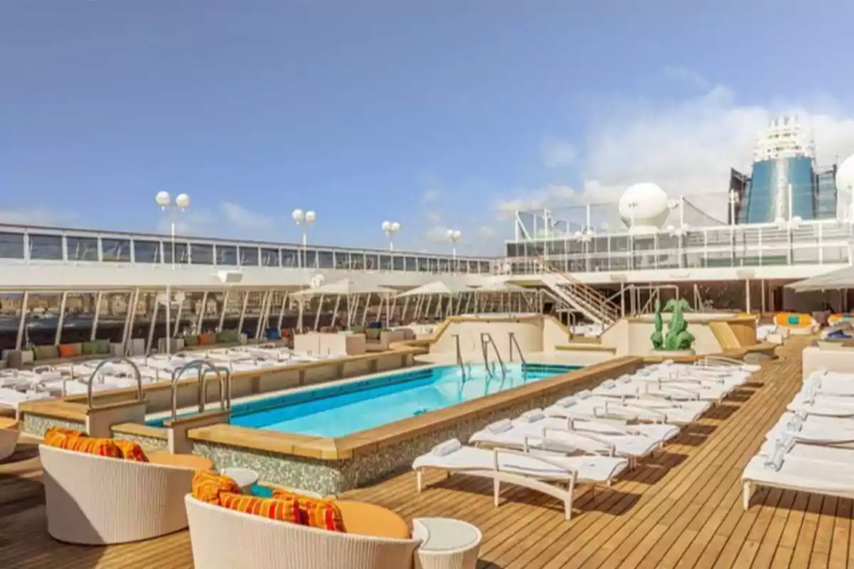 Área de piscina en la cubierta de un crucero con tumbonas y sillas alrededor.