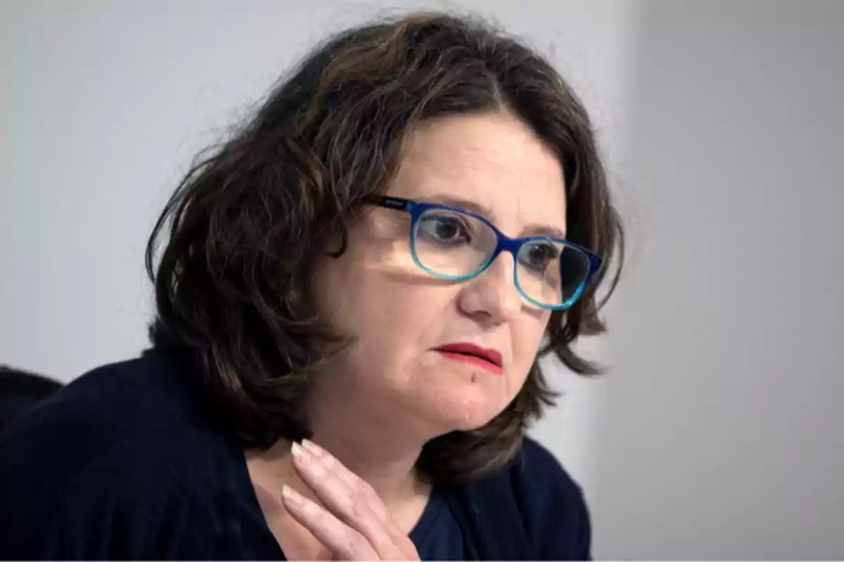Una persona con gafas azules y expresión pensativa.
