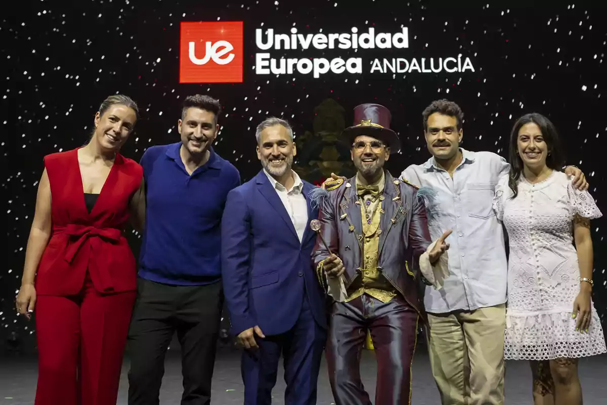 Un grupo de personas posando juntas en un escenario frente a un fondo con el logotipo de la Universidad Europea de Andalucía.