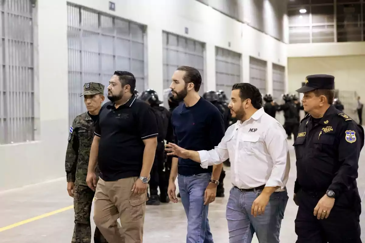 Un grupo de hombres, algunos con uniformes militares y policiales, caminan por un pasillo en lo que parece ser una instalación de seguridad.