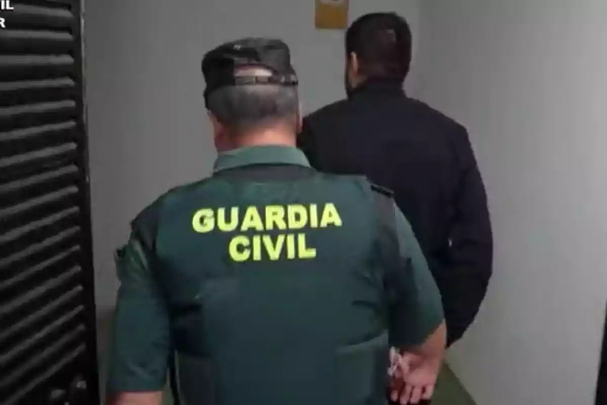 Un agente de la Guardia Civil escolta a una persona por un pasillo.