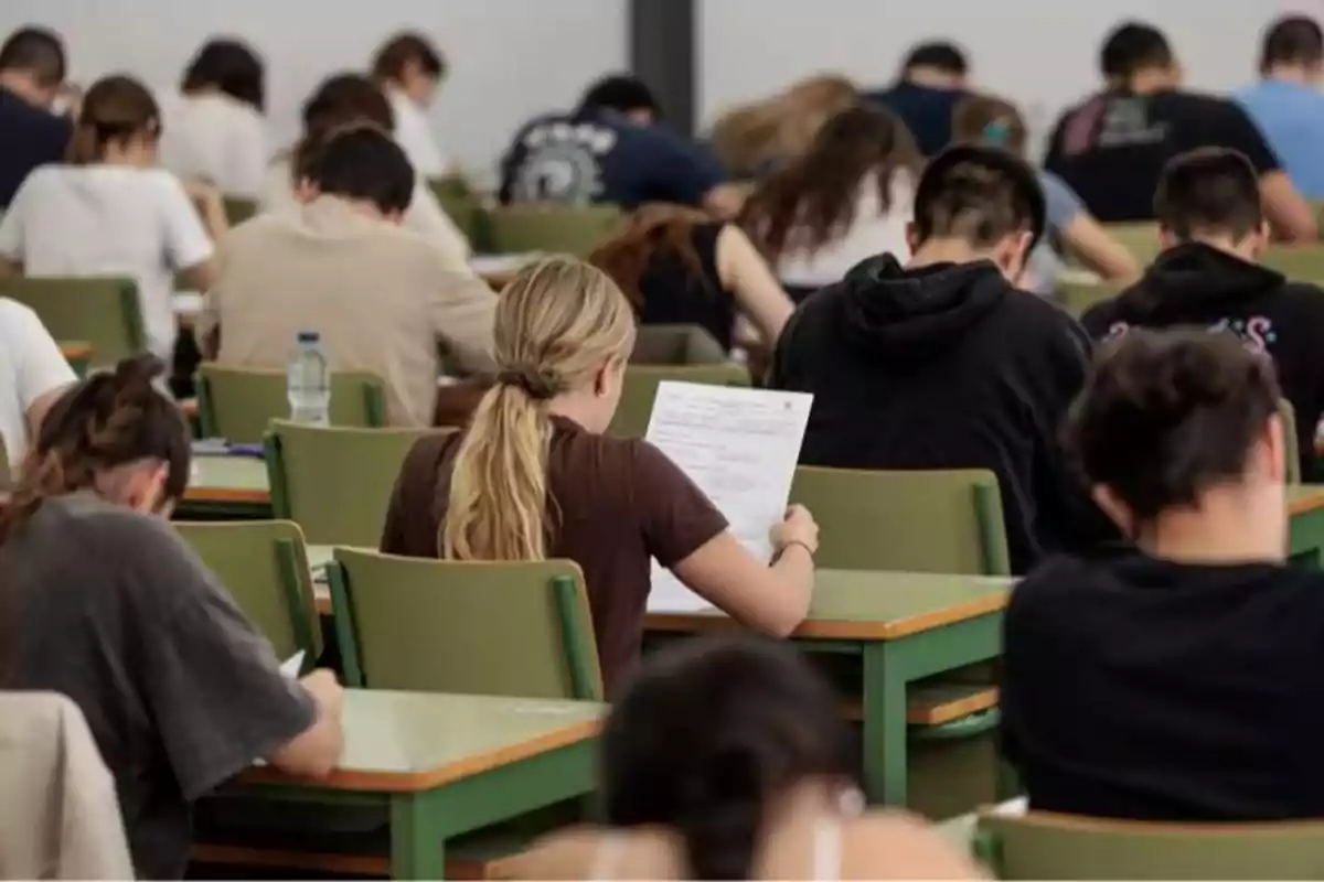 Un grupo de estudiantes sentados en pupitres realizando un examen en un aula