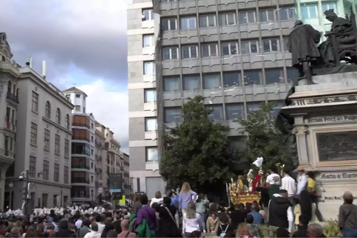 Una multitud se reúne en una plaza urbana durante un evento con un edificio moderno y una estatua en el fondo. Una multitud se reúne en una plaza urbana durante un evento con un edificio moderno y una estatua en el fondo.