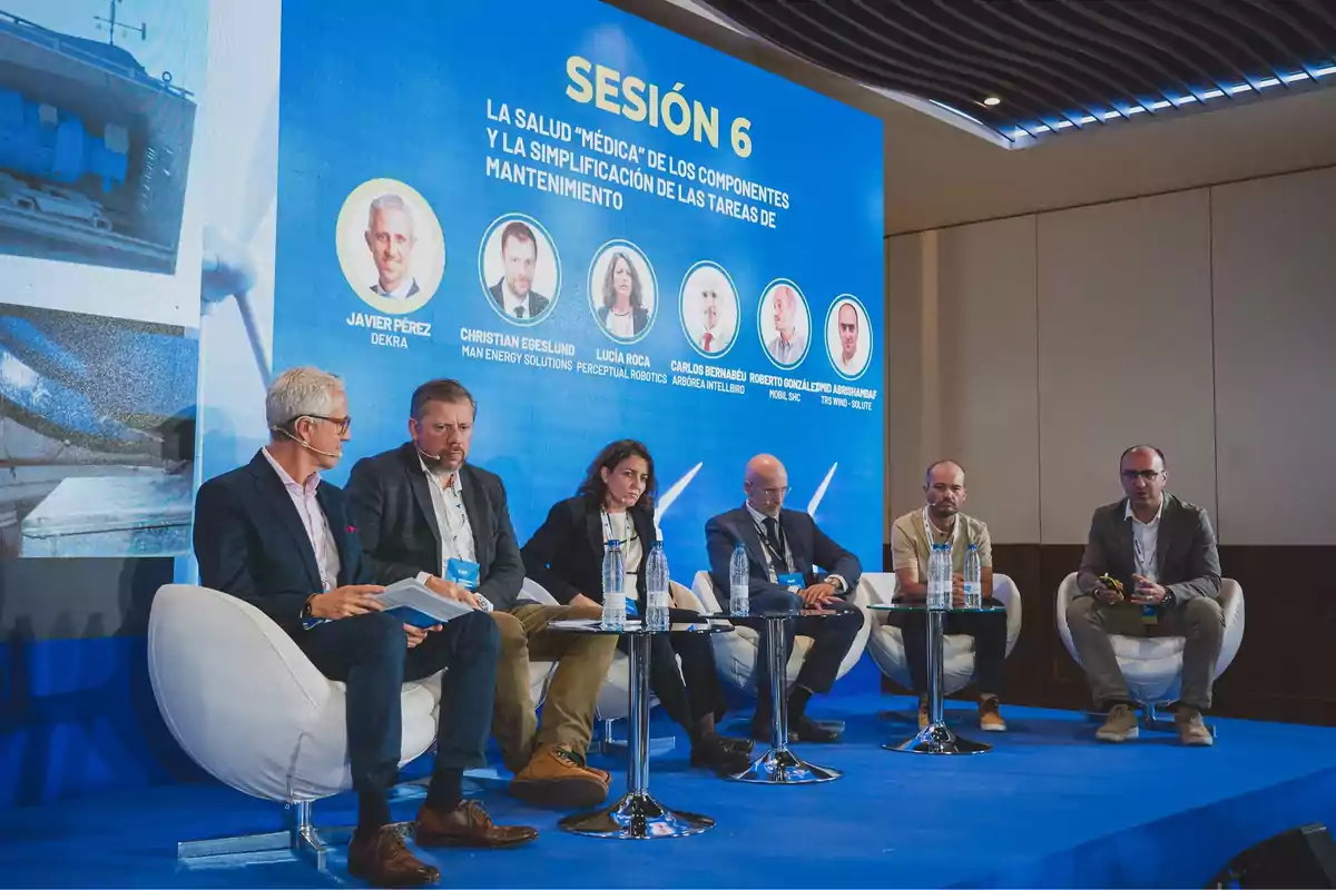 Un grupo de seis personas está sentado en un escenario participando en un panel de discusión durante un evento, con un gran cartel azul detrás que indica que es la sesión 6 sobre la salud de los componentes y la simplificación de las tareas de mantenimiento.