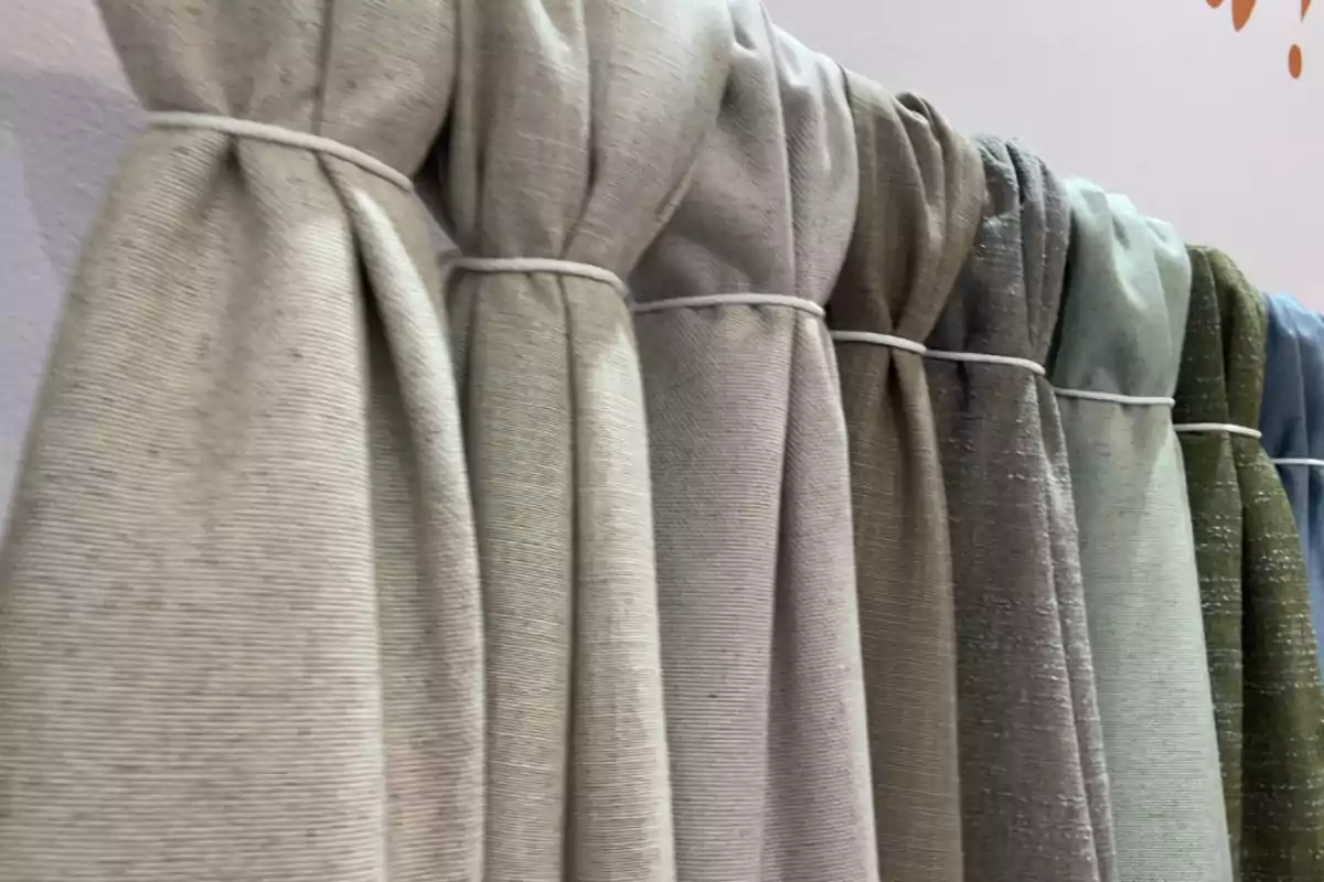 Cortinas de tela en varios tonos neutros y pastel colgadas en fila Cortinas de tela en varios tonos neutros y pastel colgadas en fila