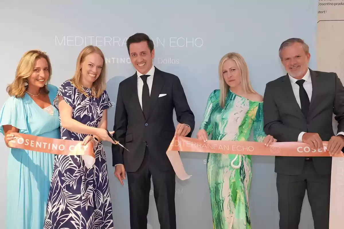 Un grupo de personas bien vestidas participa en una ceremonia de corte de cinta frente a un fondo azul claro.