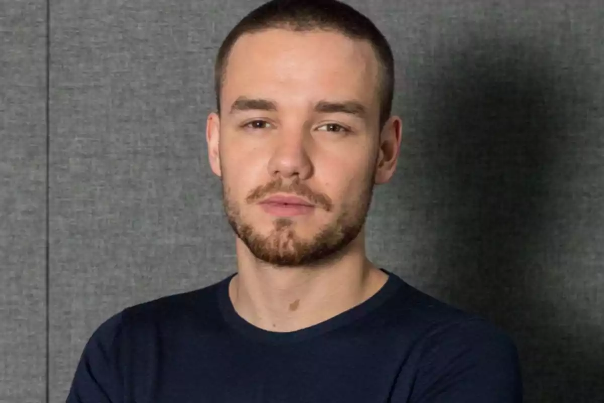 Un hombre con barba y cabello corto frente a un fondo gris.