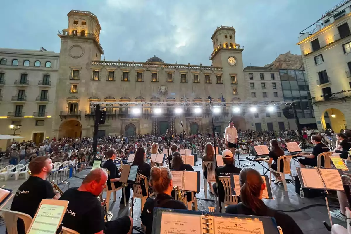 Orquesta tocando en elescenario al aire libre frente al Ayuntamiento de Alicante