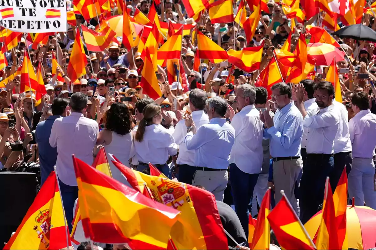 Multitud de personas en una manifestación ondeando banderas de España y aplaudiendo bajo el sol Multitud de personas en una manifestación ondeando banderas de España y aplaudiendo bajo el sol