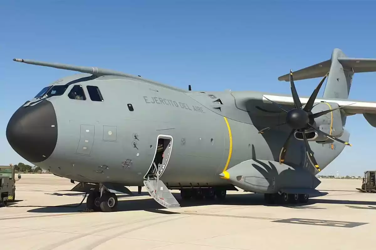 A military transport plane on a landing strip with the door open and a clear sky. A military transport plane on a landing strip with the door open and a clear sky.