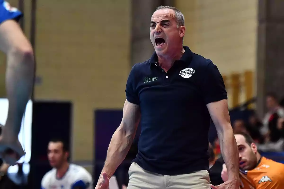 Entrenador de balonmano gritando con expresión de intensidad durante un partido en un pabellón deportivo