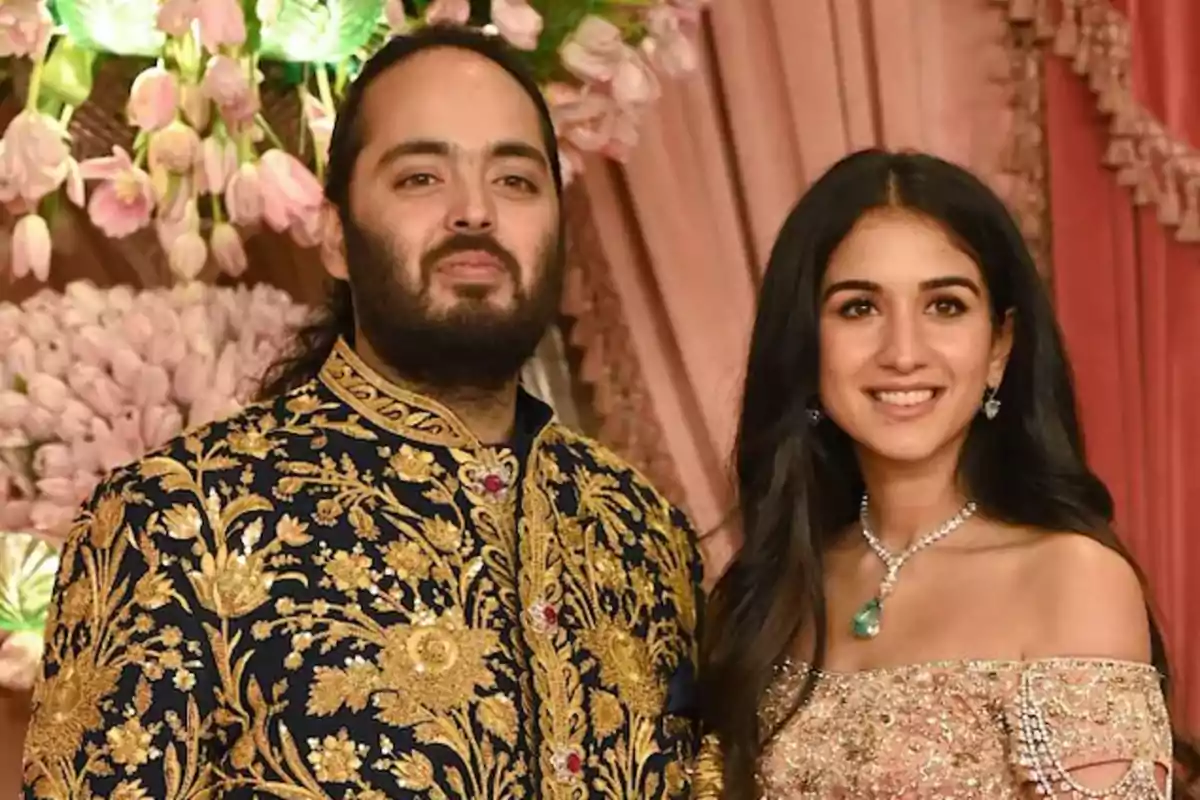 Una pareja vestida con trajes tradicionales posando frente a una decoración floral.