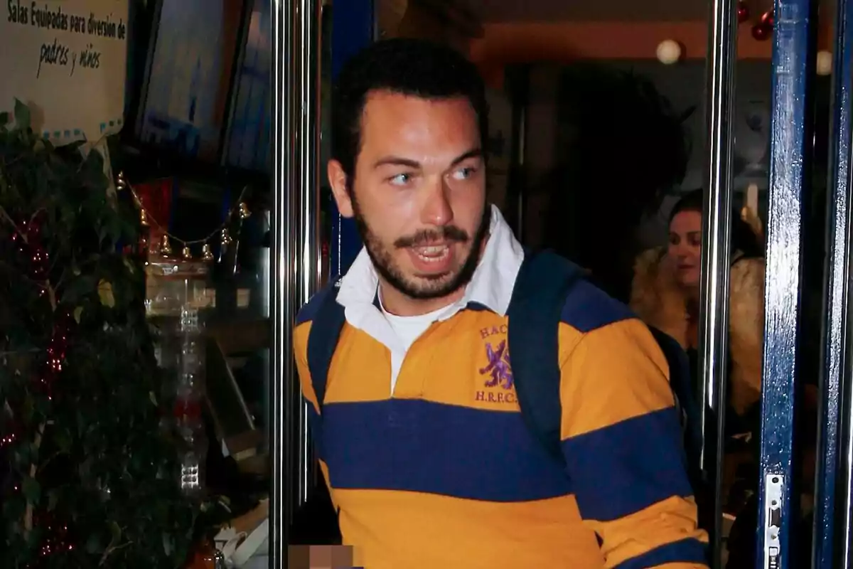 Alberto Isla con una camiseta de rayas amarillas y azules está saliendo de un lugar con puertas de vidrio. Alberto Isla con una camiseta de rayas amarillas y azules está saliendo de un lugar con puertas de vidrio.