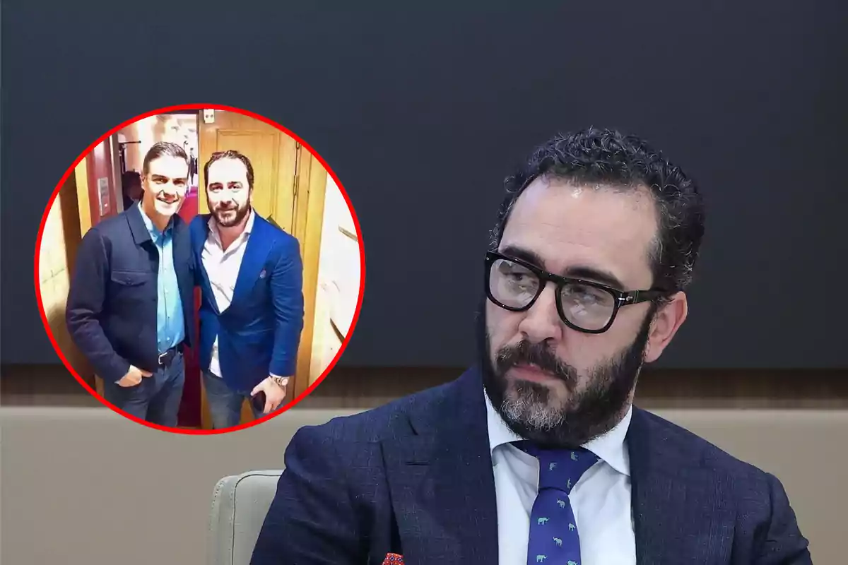 Un hombre con gafas y barba está sentado en una sala de conferencias, mientras que en un recuadro rojo se muestra una foto de dos personas posando juntas y sonriendo.