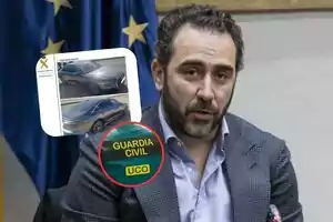 A man with a beard and jacket speaks in front of a microphone, with an overlaid image of a car and a Guardia Civil emblem.