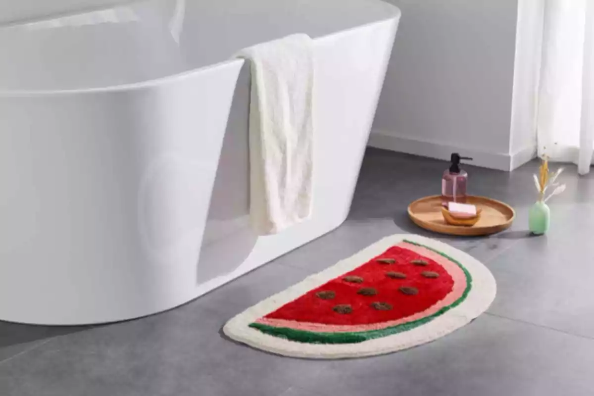 Un baño moderno con una alfombra en forma de rodaja de sandía junto a una bañera blanca, una bandeja de madera con jabón y un dispensador de jabón líquido. Un baño moderno con una alfombra en forma de rodaja de sandía junto a una bañera blanca, una bandeja de madera con jabón y un dispensador de jabón líquido.