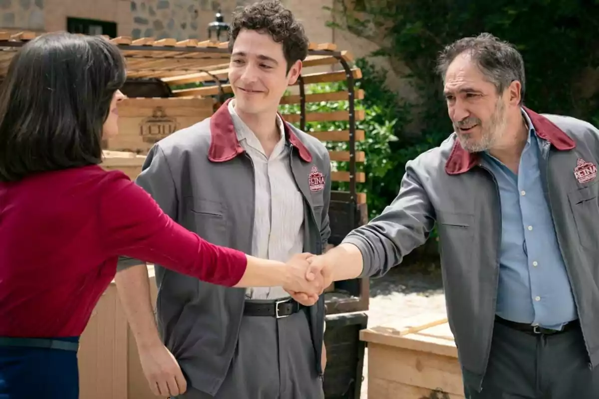 Alfonso Lara, Pablo Béjar y Carolina Lapausa se saludan cordialmente en un entorno al aire libre, dos de ellas llevan uniformes grises con detalles rojos en Sueños de Libertad.