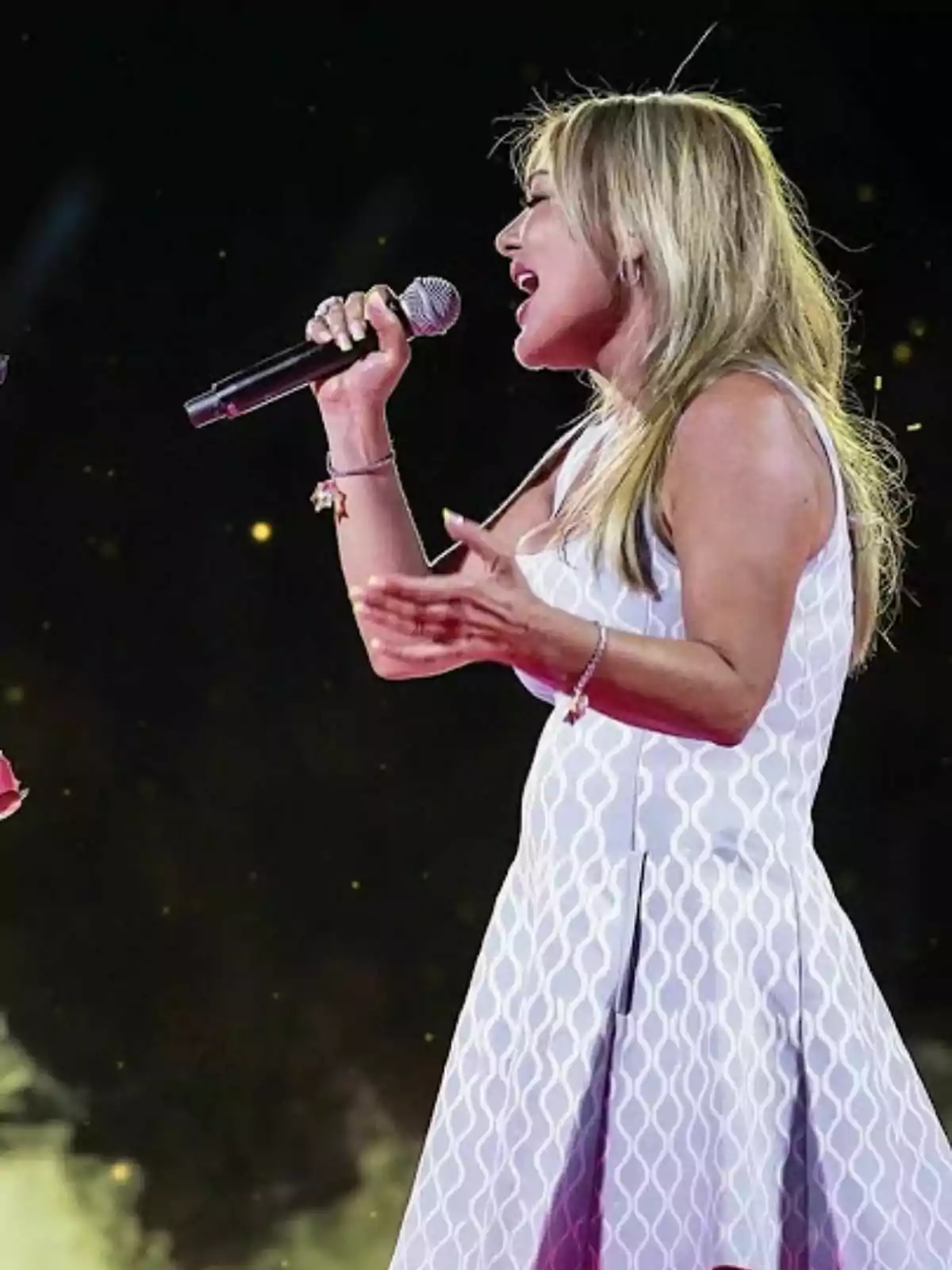 Amaia Montero cantando en un escenario con un micrófono en la mano, vestida con un vestido blanco. Captura de YouTube el 24 de julio de 2024