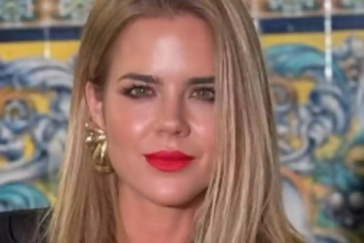 Una persona con cabello rubio y labios rojos frente a un fondo colorido. Una persona con cabello rubio y labios rojos frente a un fondo colorido.